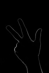 La silhouette de trois doigts de la main en clair-obscur