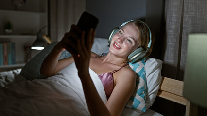 Young blonde woman doing video call lying on the bed at bedroom