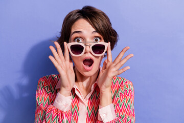 Portrait of speechless girl wear shirt fingers touch stylish sunglass staring at unbelievable sale isolated on blue color background