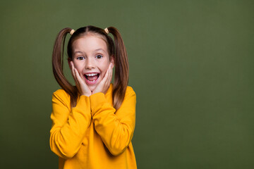 Portrait of overjoyed small kid with tails dressed yellow shirt look at discount hands on cheeks...