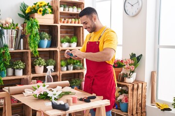 Young hispanic man florist make photo to flower by smartphone at florist