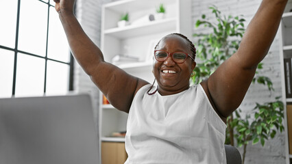 Confident african american woman, a successful business worker, raising arms in a celebrating...