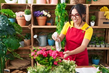 Young beautiful arab woman florist using diffuser watering plant at flower shop