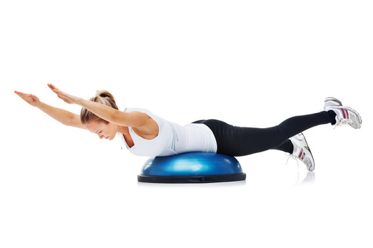 Fitness, bosu ball and woman in a studio for stretching body workout or training with balance. Sports, equipment and young female person with muscle warm up exercise isolated by white background.