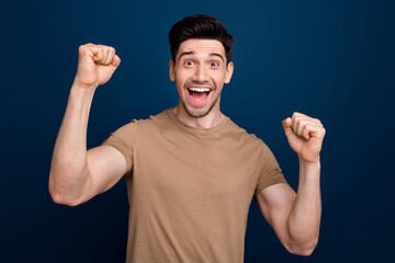 Photo of overjoyed cheerful man dressed beige stylish clothes celebrate victory isolated on dark blue color background