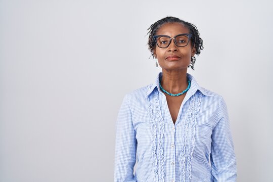 African woman with dreadlocks standing over white background wearing glasses relaxed with serious expression on face. simple and natural looking at the camera.