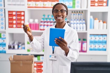 African american woman pharmacist using touchpad holding pills bottle at pharmacy
