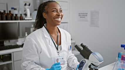 A cheerful woman scientist in a lab coat conducts research in a modern laboratory with microscope...