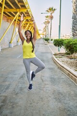 African american woman wearing sportswear doing yoga exercise at street