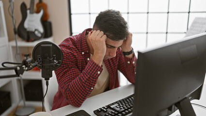 Stressed out, portrait of a young hispanic man, an upset musician facing problem with online...
