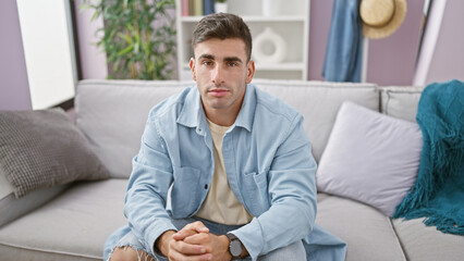Worried young hispanic man, doubting and thinking indoors, a serious expression portrayed while...