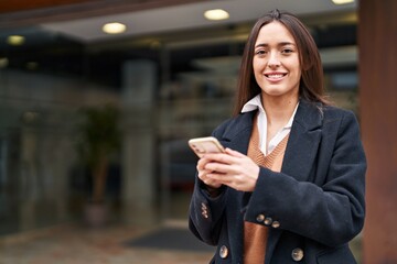 Young beautiful hispanic woman smiling confident using smartphone at street