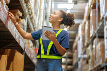 Young black African American woman holding a tablet checks inventory and checks orders from customers to deliver documents to customers in a warehouse wholesale store.