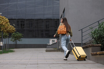 Being late. Woman with backpack and suitcase walking outdoors, back view with space for text