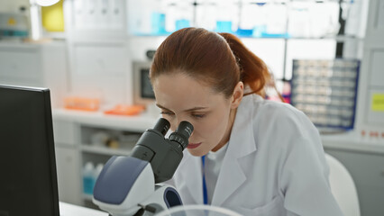 Close-up of a focused young caucasian female scientist using a microscope in a laboratory setting.