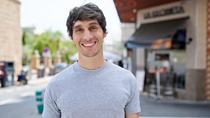 Young hispanic man smiling confident standing at street