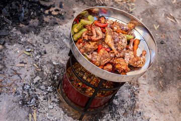 Zurbian dinner. The barrel has been uncovered and it is ready and well cooked. It contains chicken, vegetables and rice. It is placed on a wire rack and it has been transferred to the serving tray. - obrazy, fototapety, plakaty