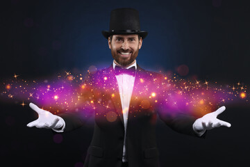 Smiling magician showing trick on dark blue background