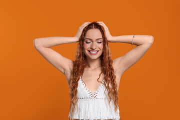 Beautiful young hippie woman on orange background