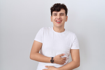 Young non binary man wearing casual white t shirt smiling and laughing hard out loud because funny...