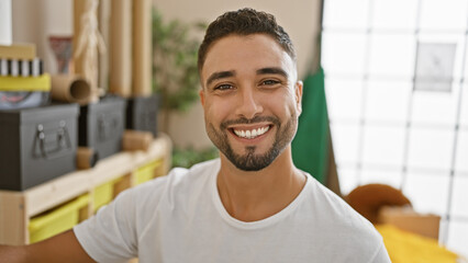 Handsome bearded man smiling in a casual indoor setting, exuding youthful confidence and...