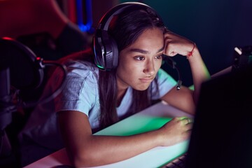 Young beautiful hispanic woman streamer stressed using computer at gaming room