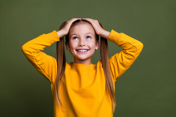 Photo of toothy beaming schoolgirl with ponytails wear yellow pullover arms on head look empty...