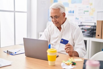 Middle age grey-haired man business worker using laptop and credit card at office