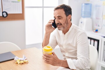 Middle age man business worker talking on smartphone working at office