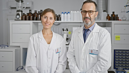 Two joyful scientists standing together, smiling amid research in their vibrant lab - a workshop of medical discoveries!