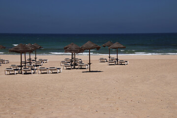 Summer scene - sunbeds under parasols at sandy beach at the sea (Peniche, Portugal) - 706523242