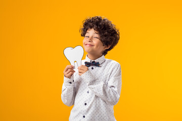 Smiling boy holding papercraft tooth. Dental health concept