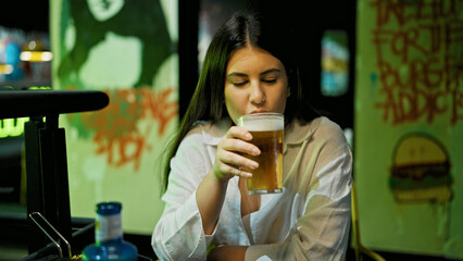 Young beautiful hispanic woman drinking beer at the restaurant