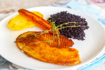 Delicious and healthy real food, grilled tilapia fish with black rice and sautéed vegetables