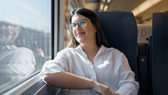 Young beautiful hispanic woman smiling happy looking through the window inside train wagon