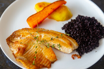 Delicious and healthy real food, grilled tilapia fish with black rice and sautéed vegetables