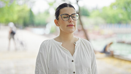 Young beautiful hispanic woman breathing with closed eyes at the park