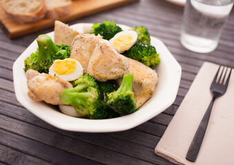Pieces of fried chicken breast with boiled broccoli and quail eggs on plate for lunch