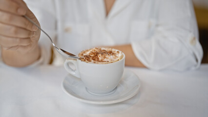Young woman drinking coffee sitting on the table at the restaurant