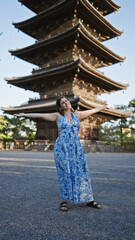 Cheerful brunette hispanic woman welcoming joy with open arms, looking around beautiful to-ji temple, reveling in kyoto's tower beauty
