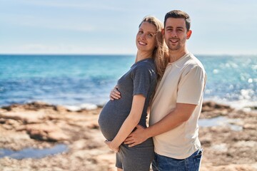 Man and woman couple hugging each other expecting baby at seaside - obrazy, fototapety, plakaty