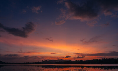 Dusk, Sunset sky clouds in the evening on twilight after sundown over silhouette mountain and lake water reflection with orange sunlight in Golden hour, Horizon sky landscape background  