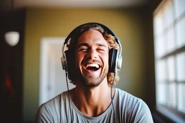 Tuinposter Happy handsome man listening to music wearing headphones at home © tiena