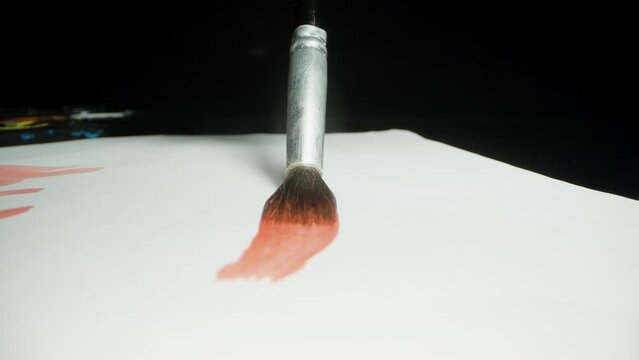 The camera follows the red line drawn by the brush on the paper. Dolly slider extreme close-up.