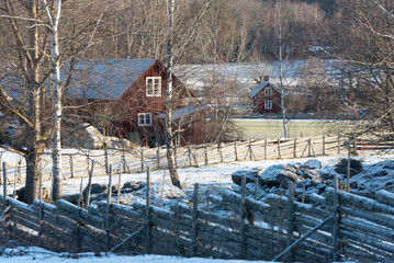 Swedish landscape in winter with traditional fences and red wooden house