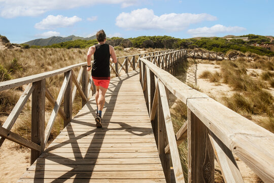Jogger l&auml;uft &uuml;ber Holzsteg, Capdepera Mallorca