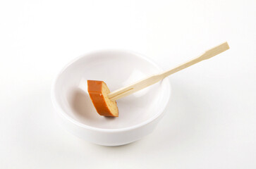 Scheibe Tofuwurst auf Holzspieß in Porzellanschale auf weißem Hintergrund