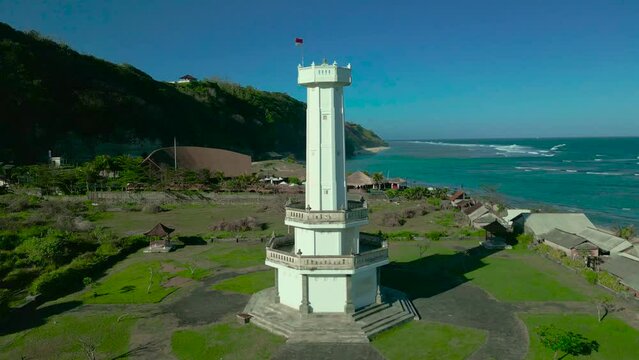 Aerial view on Towering lighthouse tower stands at Pandawa Beach, Bali, Indonesia. A majestic sight that offers stunning views of the coastline and ocean beyond.