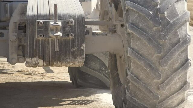 Detail of heavy machinery tires spinning on dusty construction site