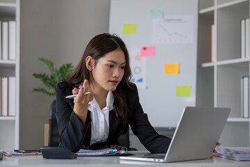Portrait of young Asian woman working on laptop in modern office Perform accounting analysis, report investment data. Financial concepts and tax system